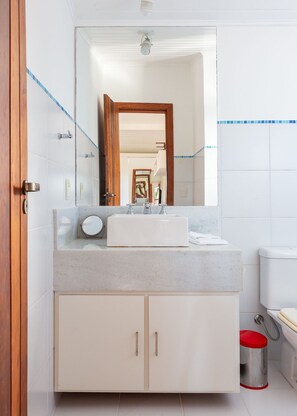 A bathroom with a white sink, a mirror, and a toilet.