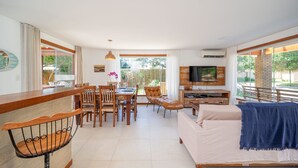 A spacious living area with a dining table, chairs, a sofa, and a TV. - Bz38 House 150m from the beach with private pool (Armação dos Búzios)