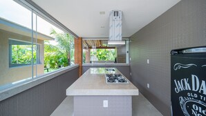 Une cuisine moderne dotée d’un îlot central, d’une grande fenêtre et offrant une vue sur la verdure.