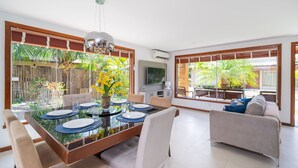 Un coin repas avec une table en verre, des chaises et un téléviseur en arrière-plan.
