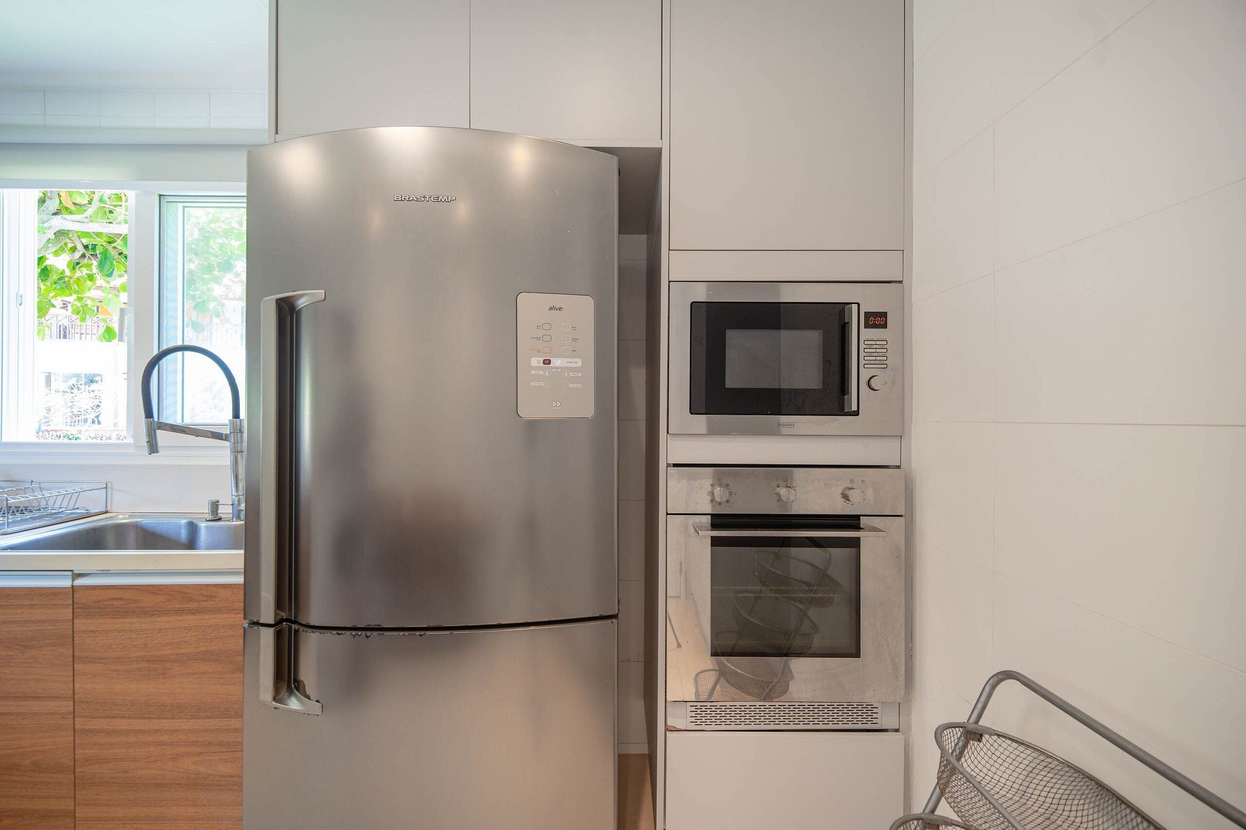 A modern kitchen with a stainless steel refrigerator, a built-in microwave, and an oven.