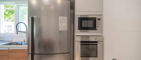 A modern kitchen with a stainless steel refrigerator, a built-in microwave, and an oven.