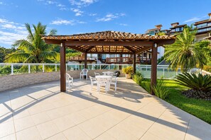 An outdoor patio area with a pergola, white plastic chairs, and a table. - Bz20 Geribá with panoramic view! 6 bedrooms (Armação dos Búzios)