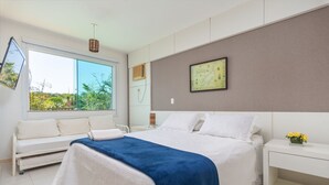 Un dormitorio moderno con una cama grande, una mesita de noche con un florero, un mapa en la pared y una ventana con vistas a zonas verdes.