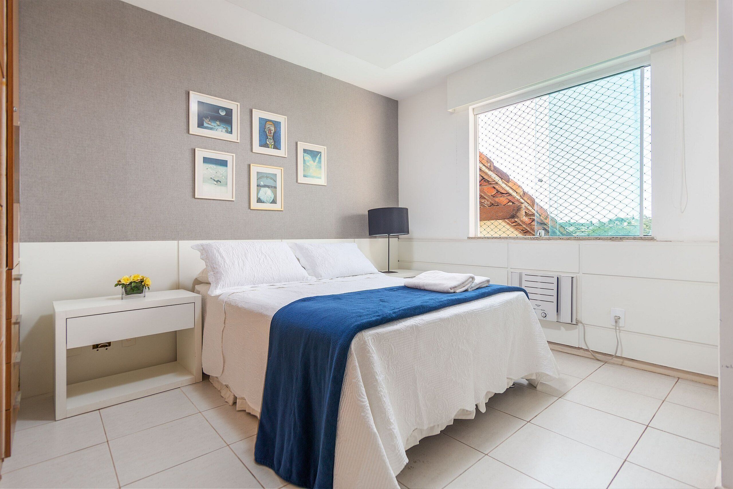 Ein Schlafzimmer mit Bett, Nachttisch, Lampe und Kunstwerk an der Wand.
