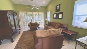 A living room with a sofa, a coffee table, a cabinet, and a ceiling fan.