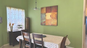 A dining area with a table, chairs, a vase with flowers, and a painting on the wall. - Right Direction Rentals Carnoustie Townhome (Port St. Lucie)