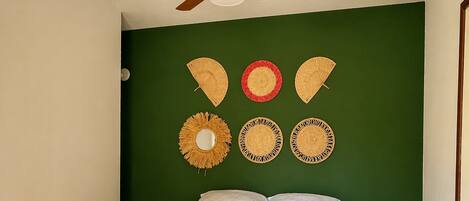 A bedroom with a bed, a ceiling fan, and wall decorations.