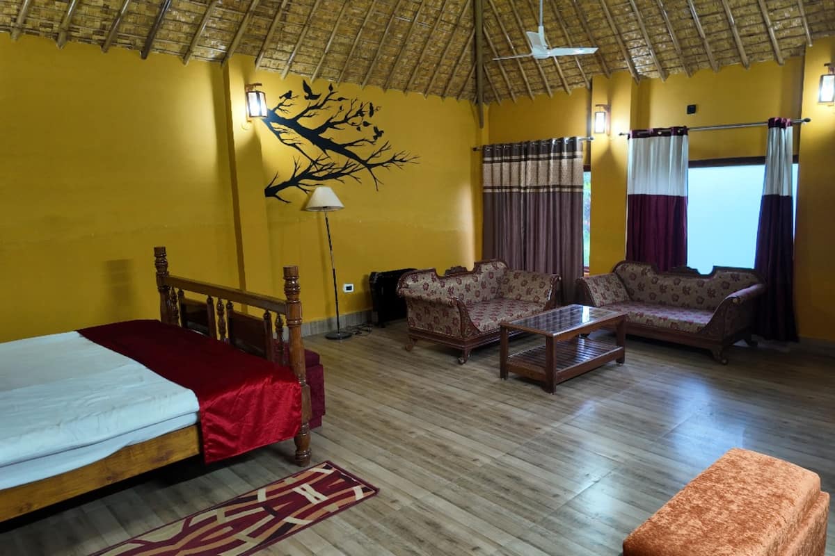 A room with a bed, two sofas, a coffee table, a wooden cabinet, a wall mural, and a window with curtains.