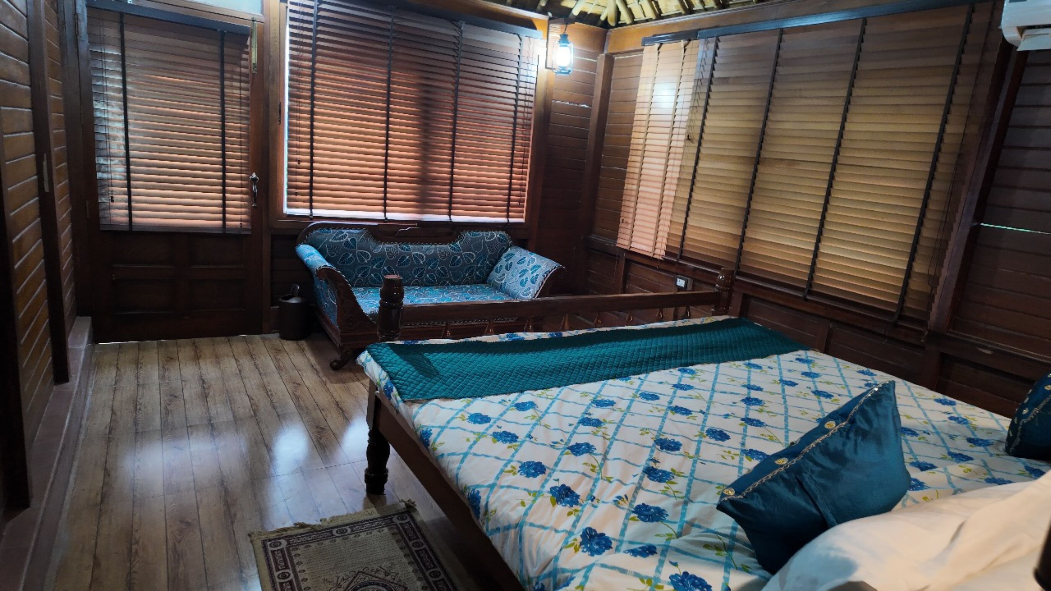 A traditional wooden room with a bed, a bench, and a window with wooden blinds.