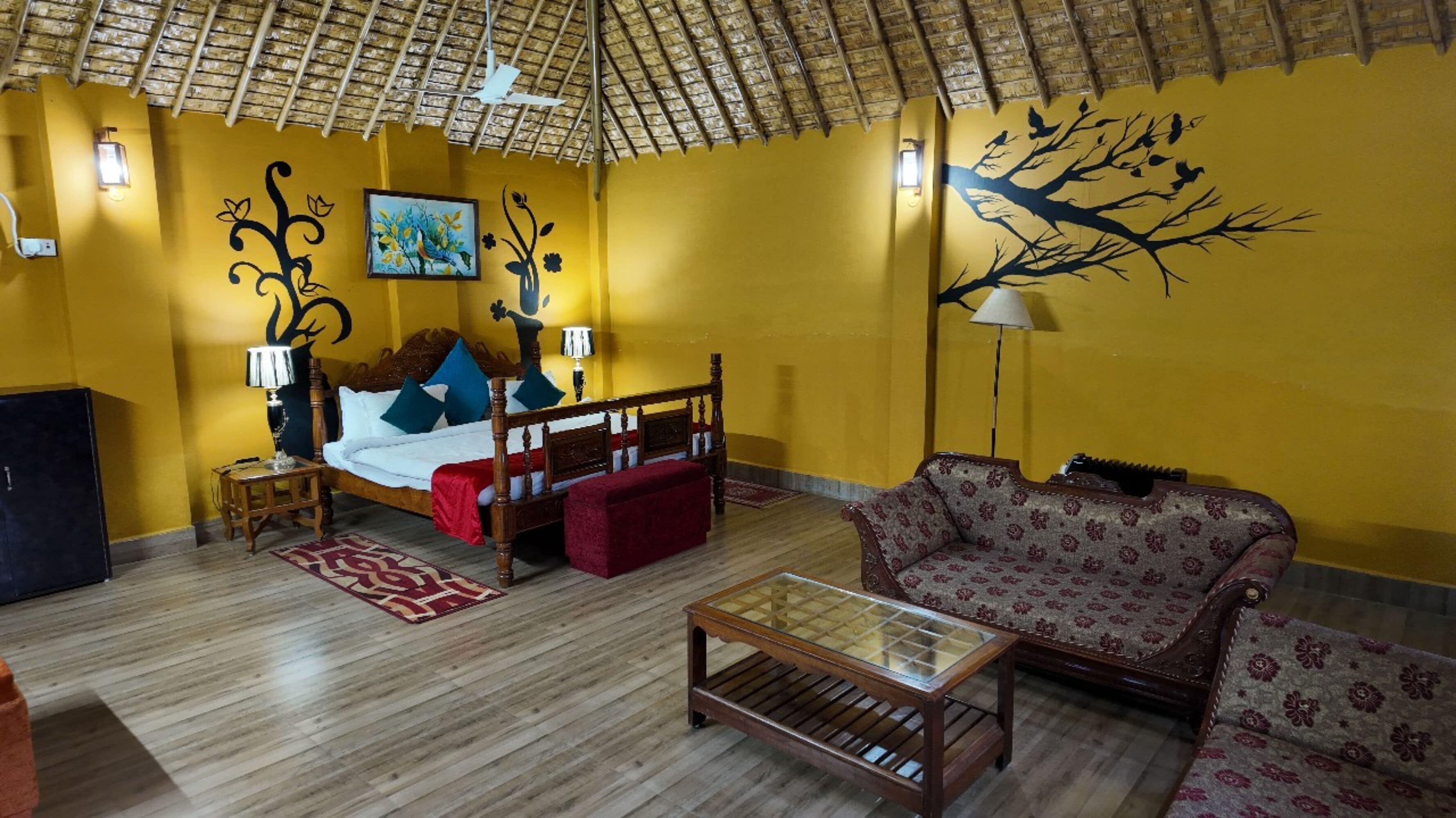 A room with a bed, a sofa, a coffee table, and a lamp.
