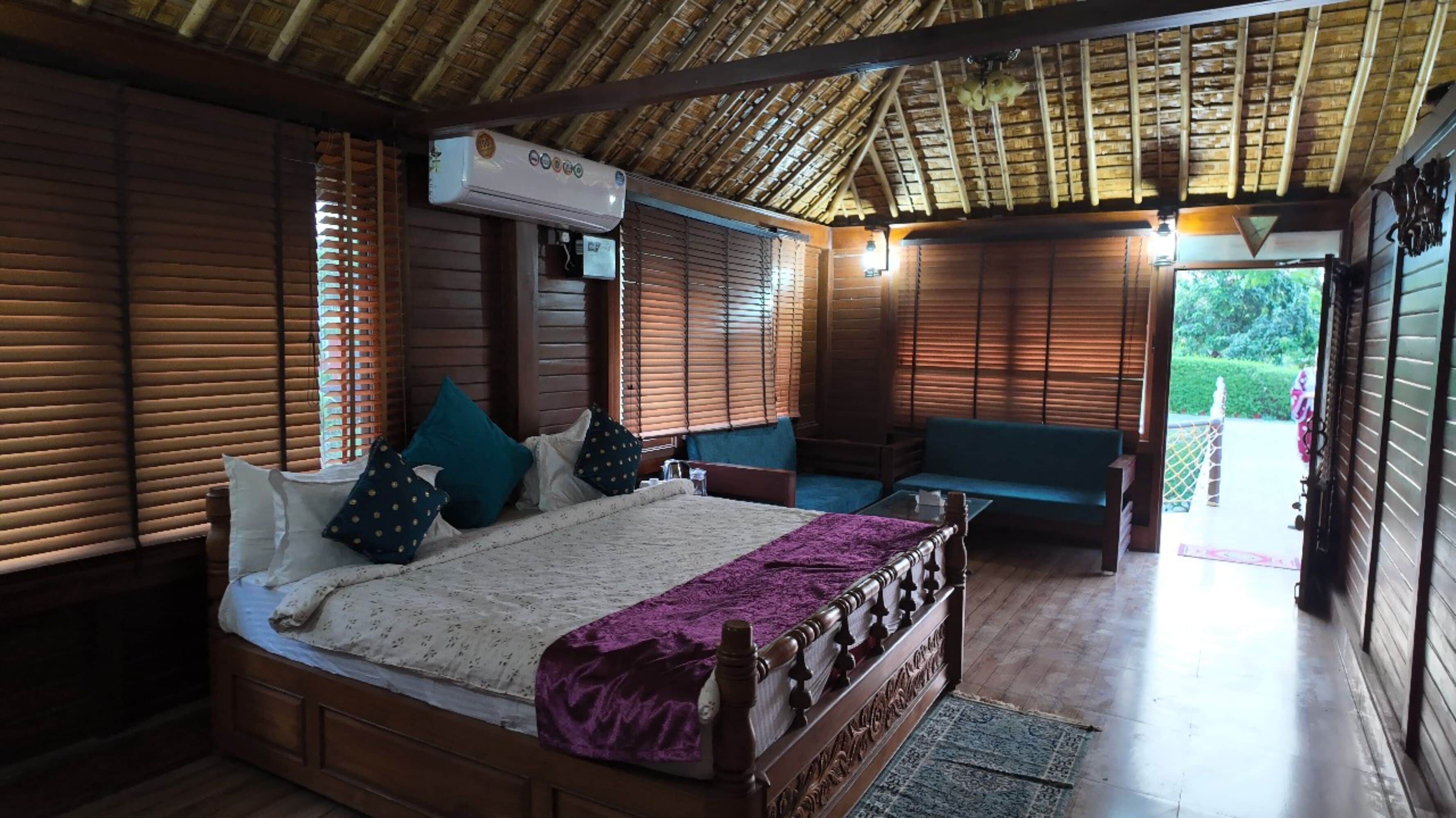 A wooden-framed room with a bed, a sofa, and a ceiling fan.