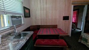 A compact kitchen with a granite countertop, a sink, a built-in bench, and a window with blinds. - Squaw Valley Motel Room #1 (Yokuts Valley)