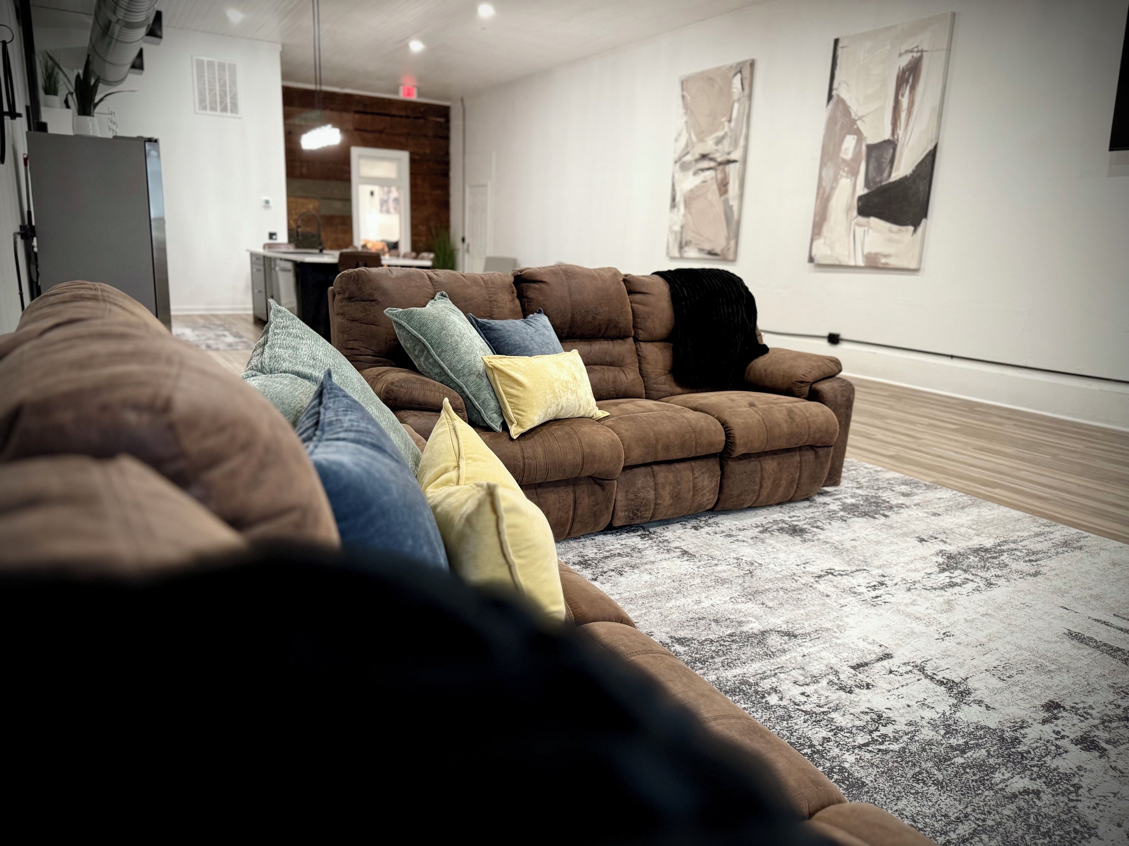A modern living room with a sectional sofa, a dining area, and abstract wall art.