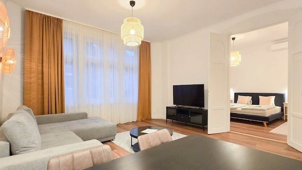 Una sala de estar moderna con sofá, televisor y mesa de comedor.