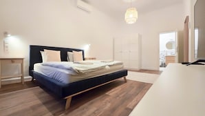 Un dormitorio con cama, mesitas de noche, armario, lámpara colgante y televisión.