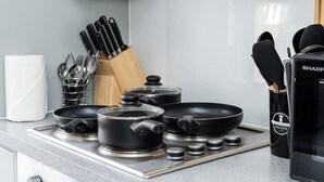 A kitchen with a gas stove, pots, pans, and a knife block.