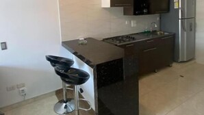 Una cocina moderna con una isla central, taburetes de bar, horno integrado y un refrigerador de acero inoxidable.