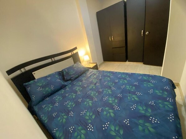 A bedroom with a bed, a nightstand, and a wardrobe. - Apartamento comodo central (Cali)