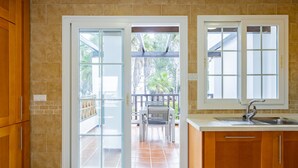 Una cocina con armarios de madera, encimera blanca, pileta y ventana.