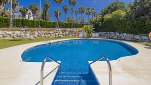 Una piscina con una pared de piedra y palmeras al fondo.