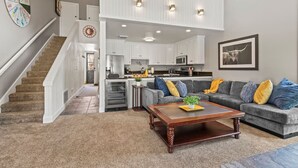A spacious living area with a staircase leading to a second floor, a kitchen with white cabinets, and a dining area. - Steps to Ski*Sleeps 8*Hot Tub* (Park City)