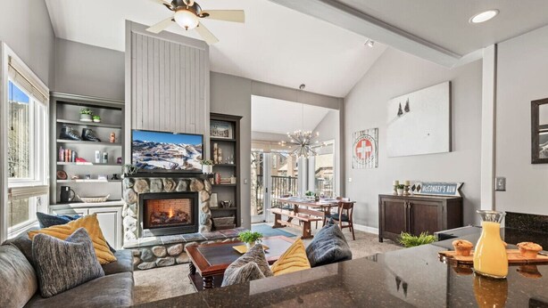 A spacious living room with a stone fireplace, a large window, and a dining area. - Steps to Ski*Sleeps 8*Hot Tub* (Park City)