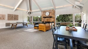A spacious room with a high ceiling, a stone fireplace, a ping pong table, and a dining area with a large table and chairs. - Steps to Ski*Sleeps 8*Hot Tub* (Park City)