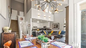 A spacious dining area with a high ceiling, modern chandelier, and a view of the kitchen and living area. - Steps to Ski*Sleeps 8*Hot Tub* (Park City)