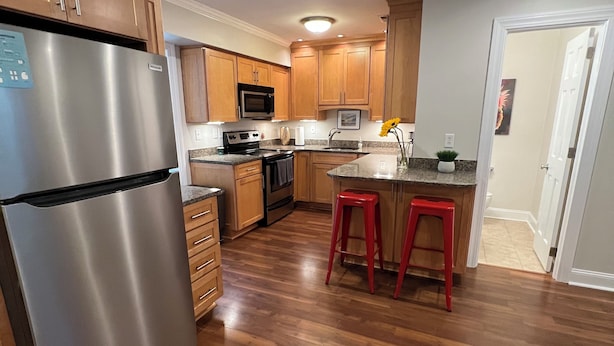 Una cocina moderna con armarios de madera, electrodomésticos de acero inoxidable y piso de madera.