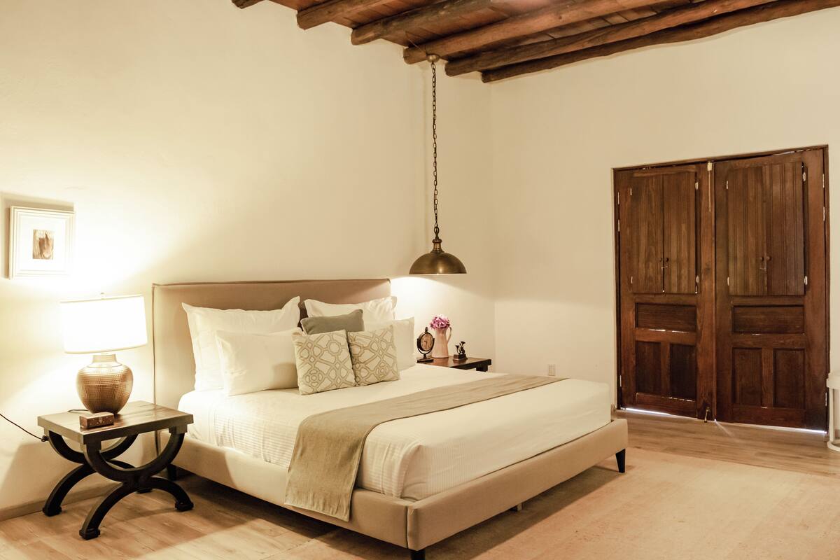 A bedroom with a bed, bedside table, lamp, and wooden wardrobe.