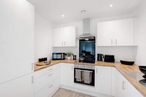 Une cuisine moderne avec des meubles blancs, un four encastré, un four à micro-ondes et une cuisinière.