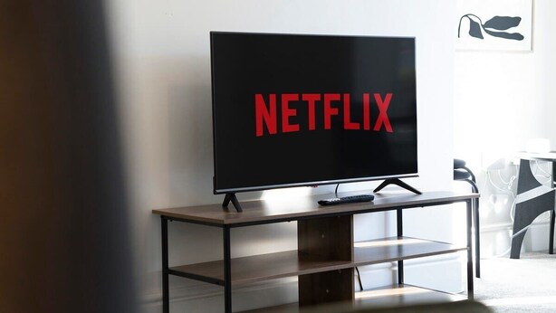 A television on a wooden stand with a black frame, displaying the Netflix logo.