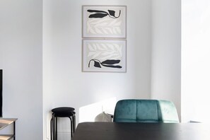 Une pièce comprenant un lit, une chaise et deux œuvres d’art abstraites encadrées accrochées au mur.