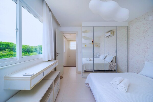 A modern bedroom with a large window, a bedside table, a bed with rolled towels, a wardrobe, and a mirror. - Bz68 Centro Casa piscina priv 6 quartos (Buzios)
