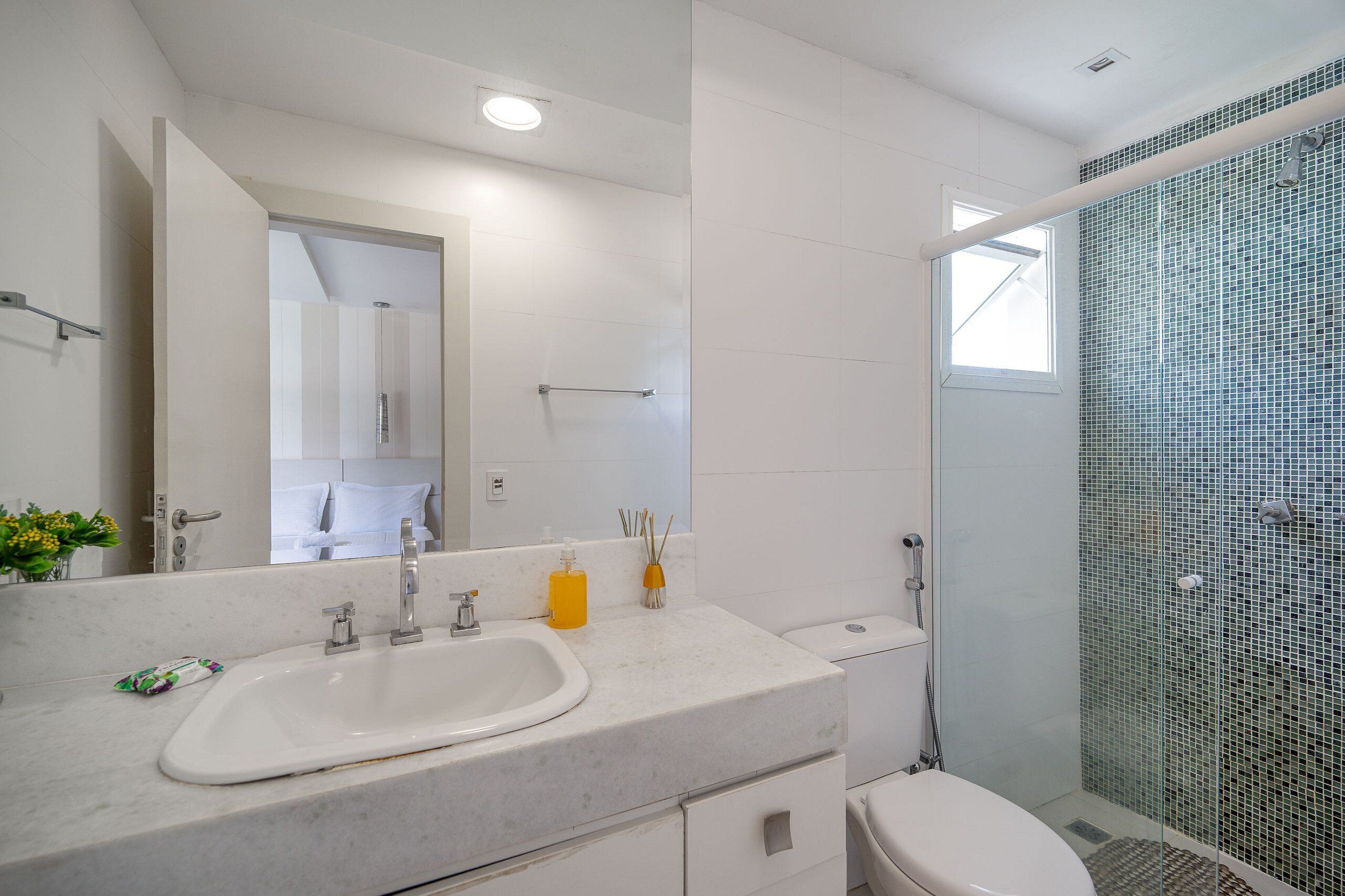 A bathroom with a white sink, mirror, and shower.