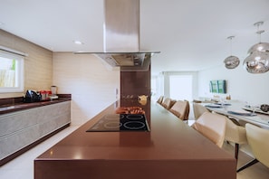 Una cocina moderna con una isla central, electrodomésticos de acero inoxidable y un comedor con una mesa larga y sillas.