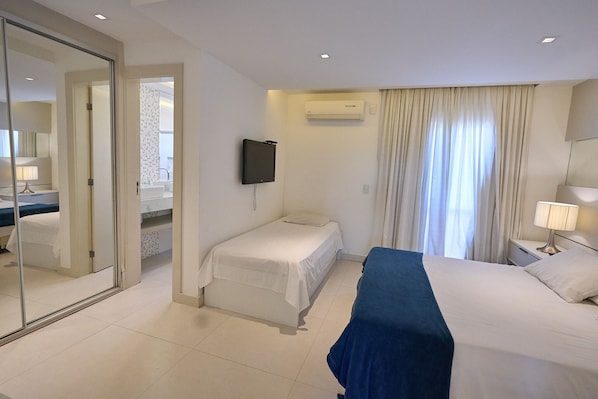 A hotel room with a bed, a desk, a chair, a TV, and a window with curtains.