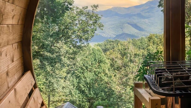 A wooden cabin with a view of a forest and mountains.