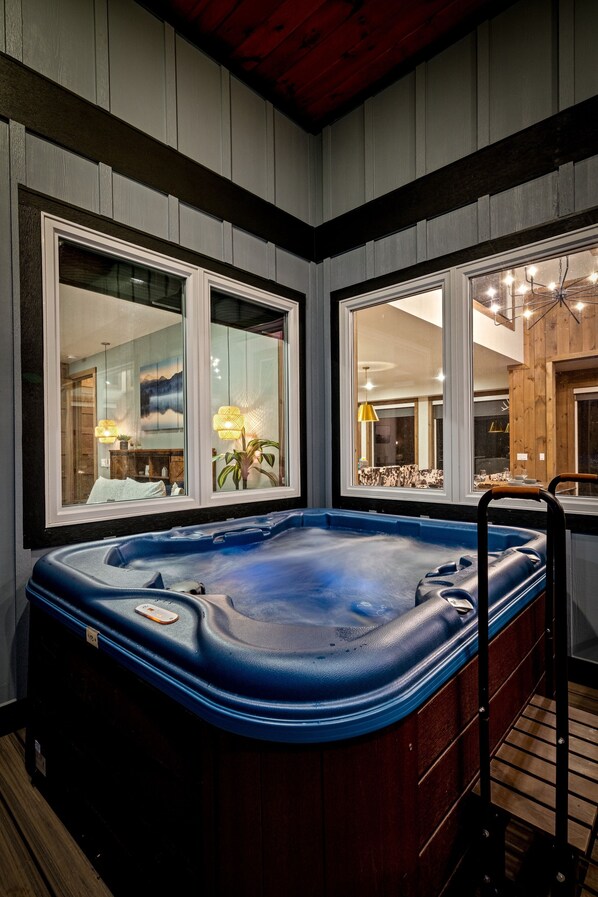 Un jacuzzi en una habitación con paredes de madera y ventanas amplias.