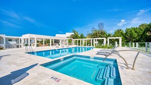 A swimming pool with a 4 FT depth marker, surrounded by a covered area with chairs and a pergola.