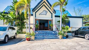 A building with a distinctive shark-shaped roof, a staircase with blue and white patterns, and several potted plants. - Sunset Point: Chic Meets Luxury, Sophisticated Style Meets Ocean Serenity (West Bay)