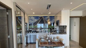 Una cocina moderna con comedor, que incluye una isla grande, electrodomésticos de acero inoxidable y un mural en la pared.