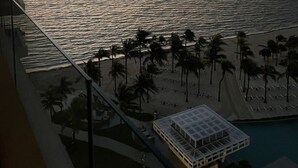 Vista a la playa con palmeras y un edificio con techo de vidrio.