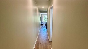 A narrow hallway with wooden flooring and white walls. - Cedar Bucket Lofts - Cozy 2-bedroom apartment in Oxford! (Oxford)