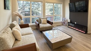 A modern living room with a sectional sofa, a glass coffee table, and a large TV.