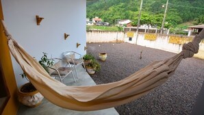 Un hamac sur un balcon donnant sur un quartier résidentiel et des collines.