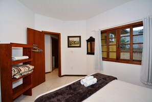 Habitación de hotel con cama, armario, ventana con cortinas y un cuadro en la pared.