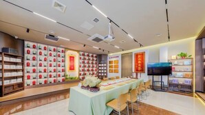 A modern interior with a long table set for dining, surrounded by chairs, and shelves with neatly arranged items on the walls. - Youpin Hotel (Linyi)