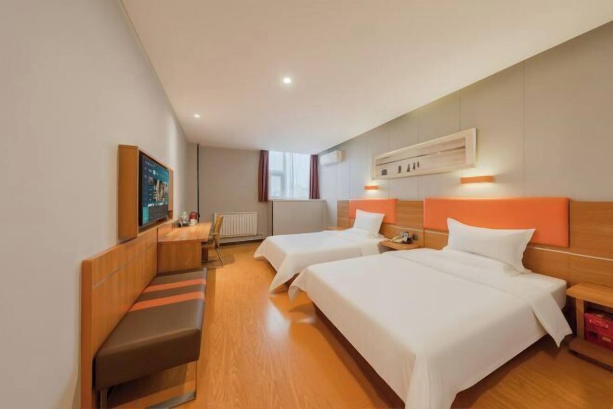 A hotel room with two beds, a seating area, a TV, and a window.